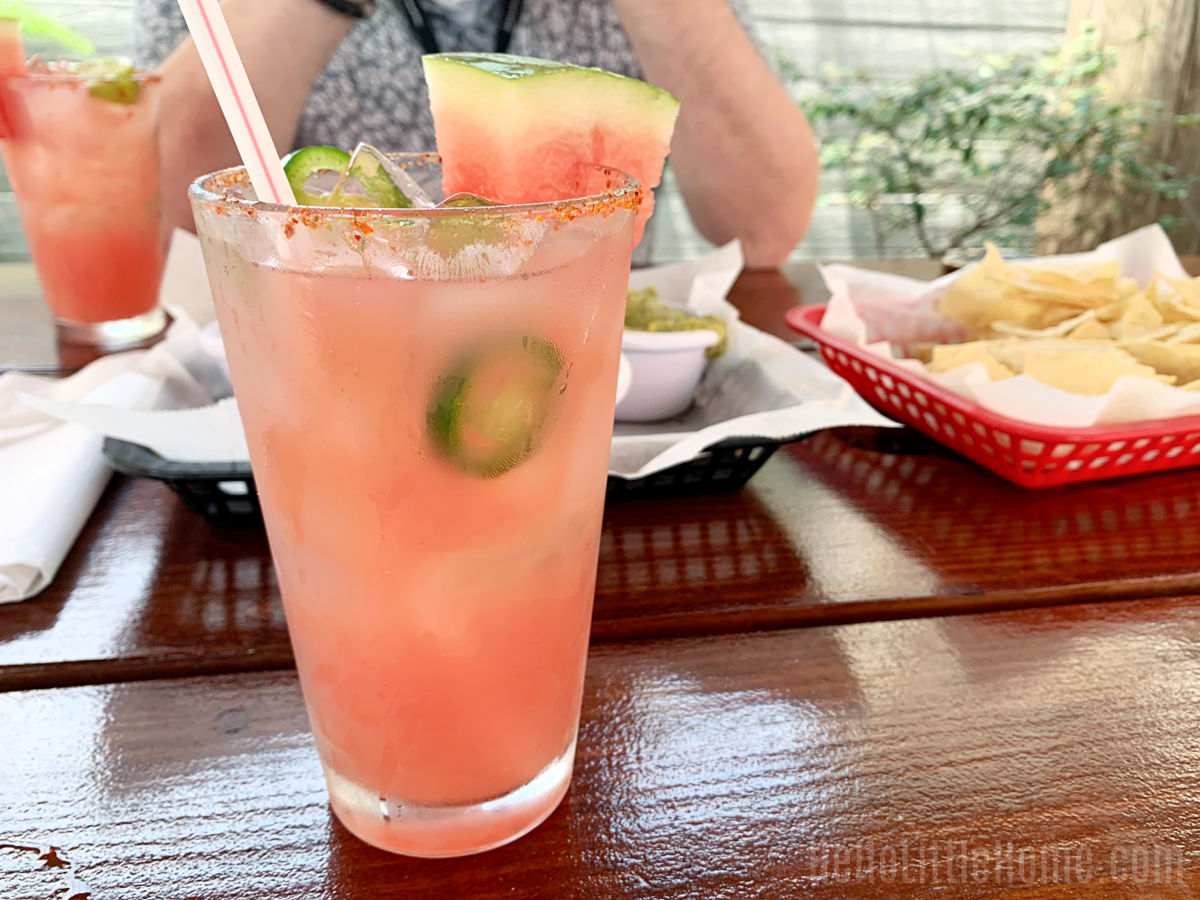 A watermelon margarita and chips on a wood table at Juan's Flying Burrito in New Orleans.