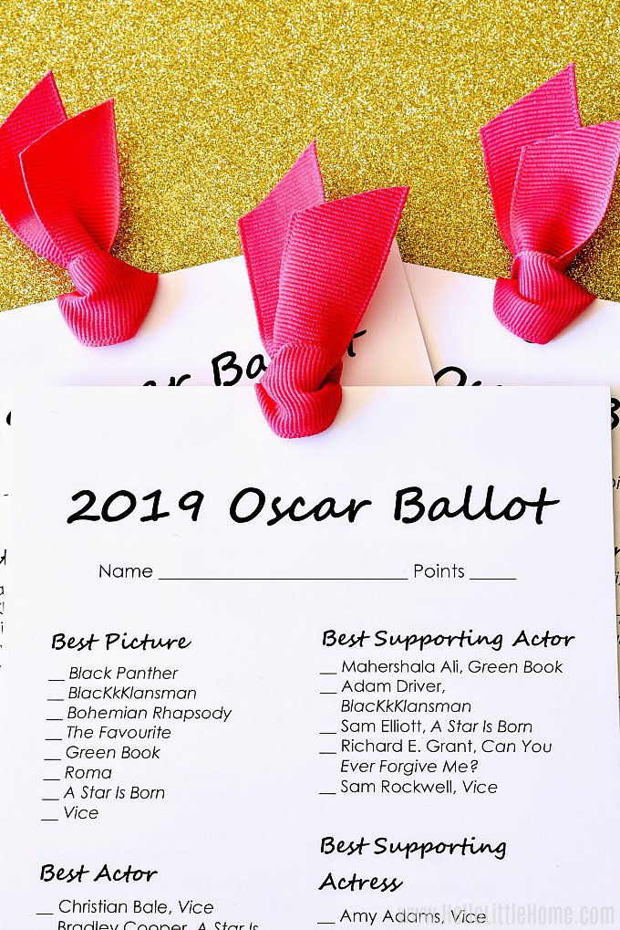 Printable Oscar Ballot for 2019 tied with pink ribbon on a gold glitter background.