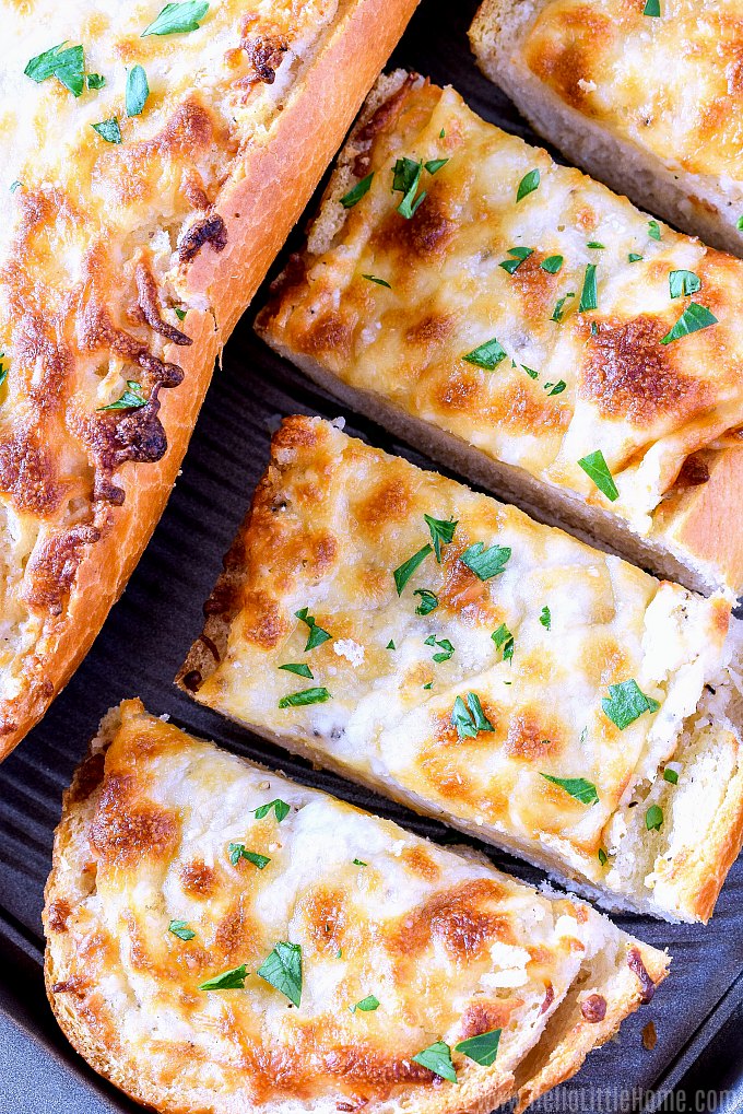 Slices of garlic cheese bread on a baking sheet.