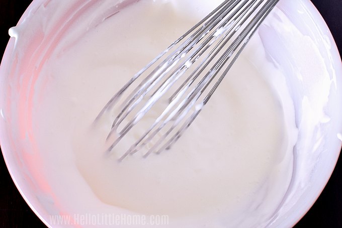 A whisk in a bowl of whipped cream.