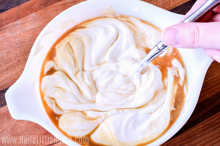 Mixing Greek yogurt, maple syrup, and vanilla together in a bowl.