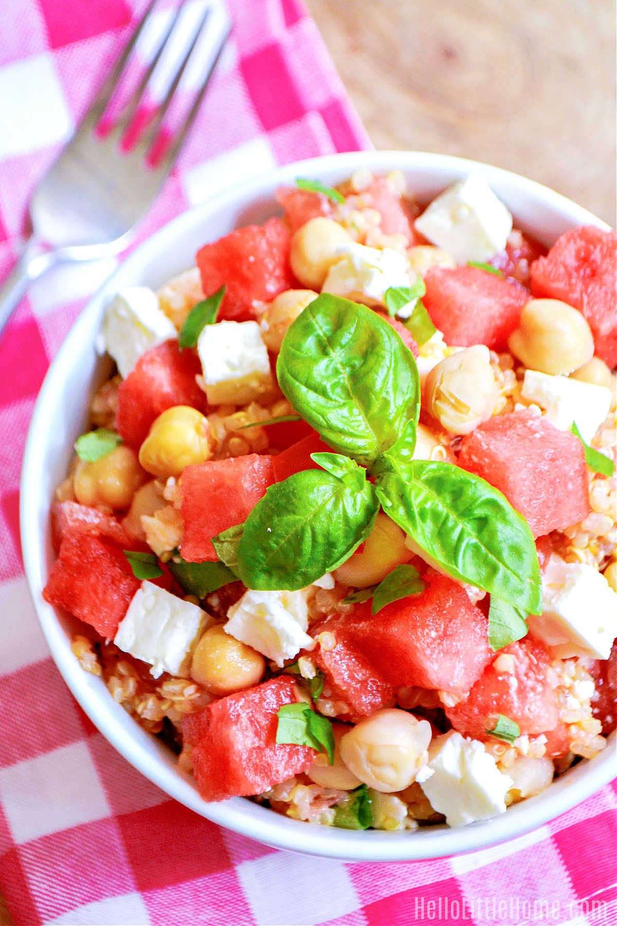 A bowl of the salad and a fork on a checked napkin.