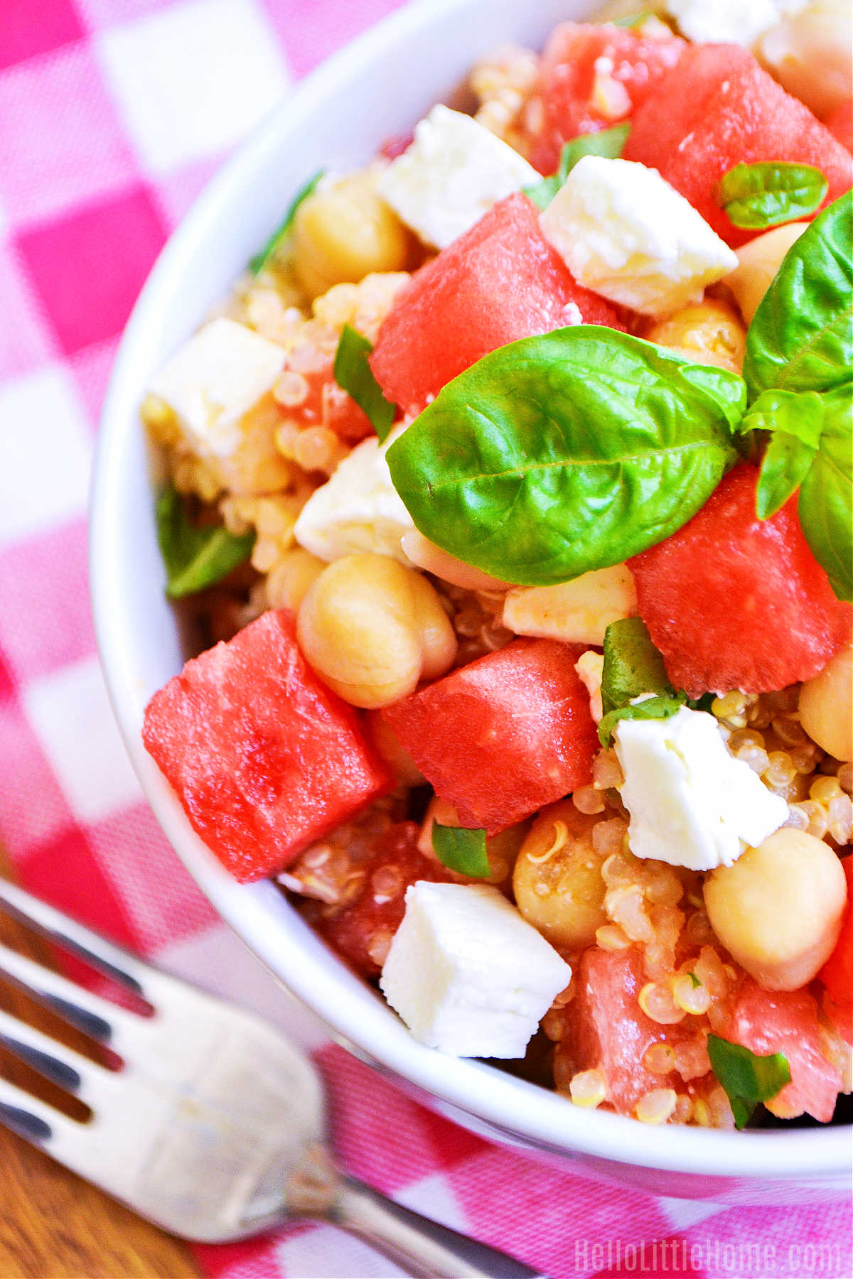 The finished salad, a napkin, and fork on a wood table.