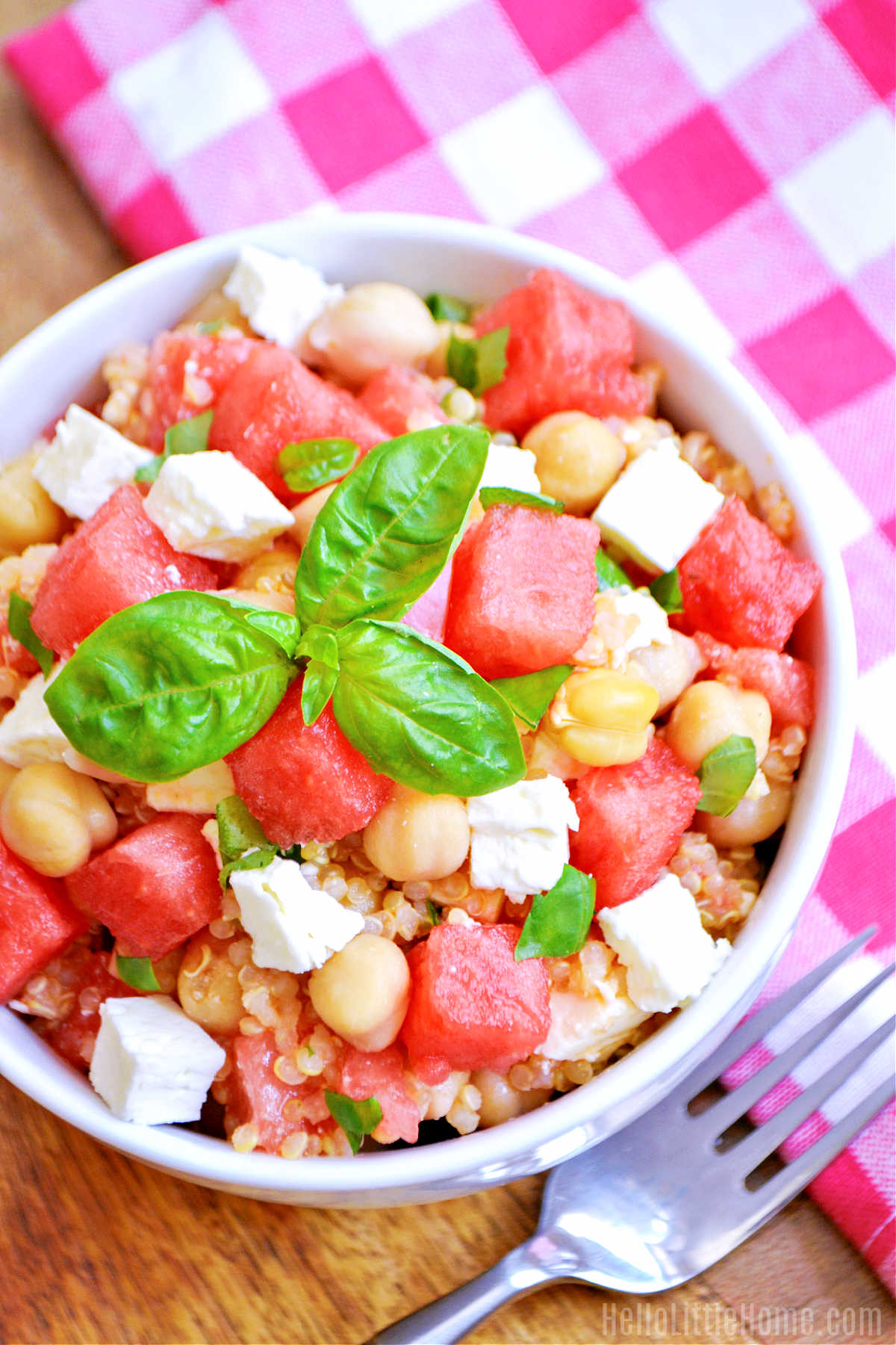 The Watermelon Feta Quinoa Salad, a napkin, and fork on a wood table.