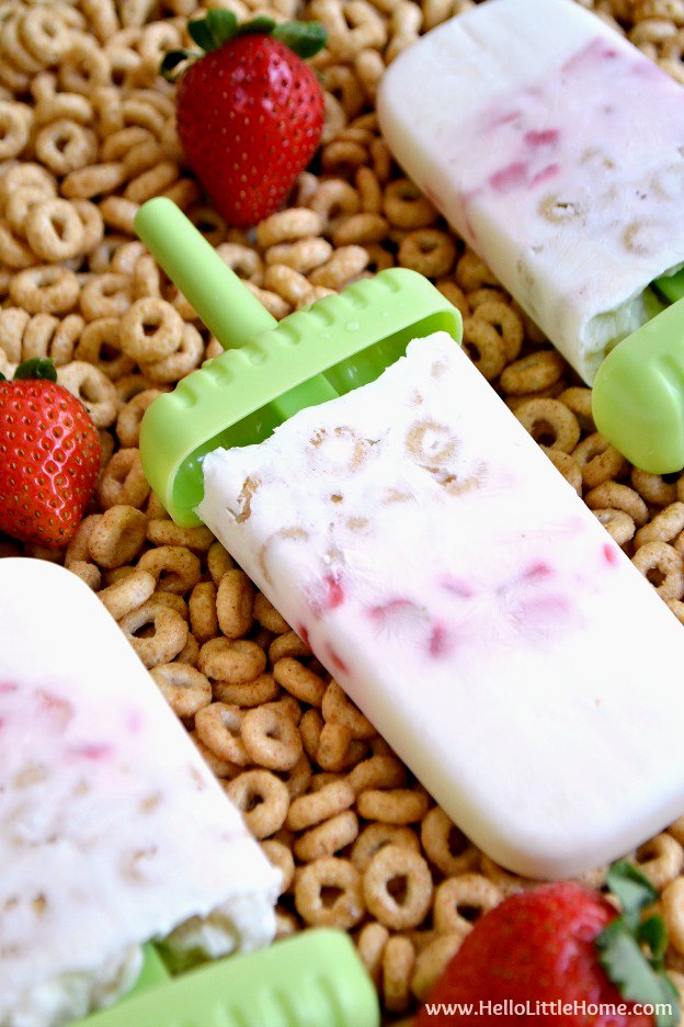 Three Breakfast Cereal Popsicles on a tray of Cheerios.