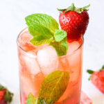 Closeup of the finished fresh Strawberry Mojito garnished with mint and a berry.