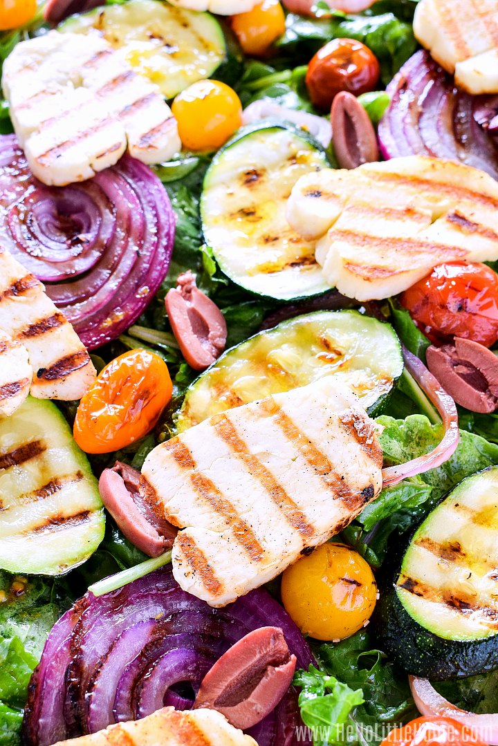 A closeup of a salad topped with grilled vegetables and halloumi.