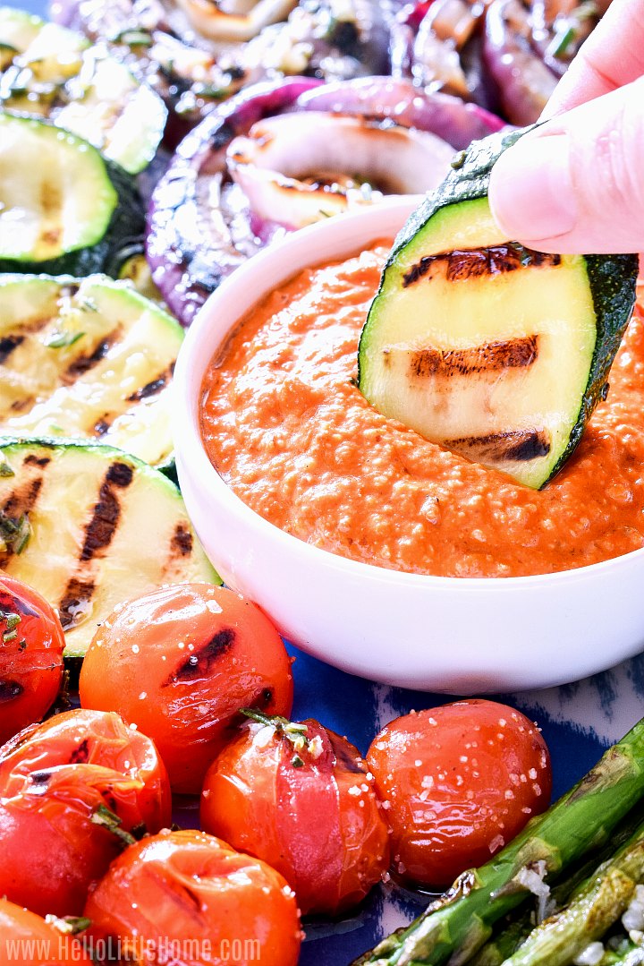 Dipping grilled zucchini in romesco sauce.