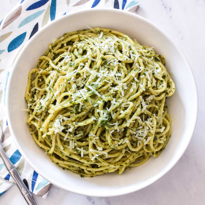 A bowl of Pesto Pasta and a patterned napkin on a marble counter.