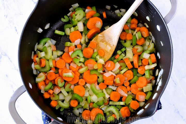 Sauteing onions, carrots, and celery in a large pot.