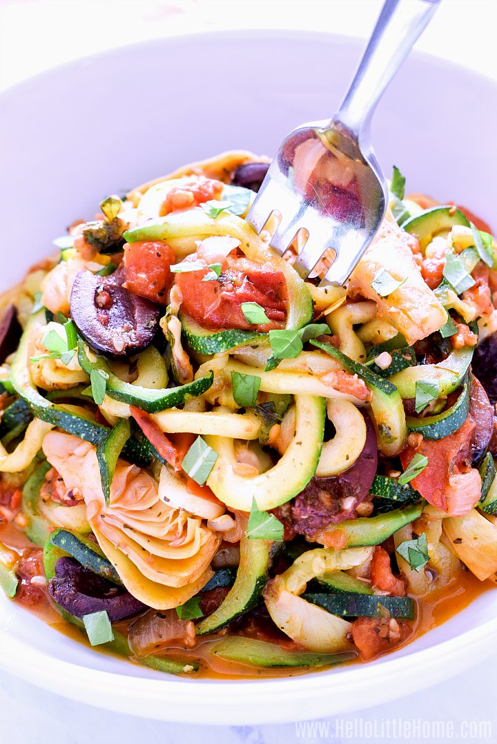 A fork twirling Zucchini Pasta with Tomato Artichoke Sauce.