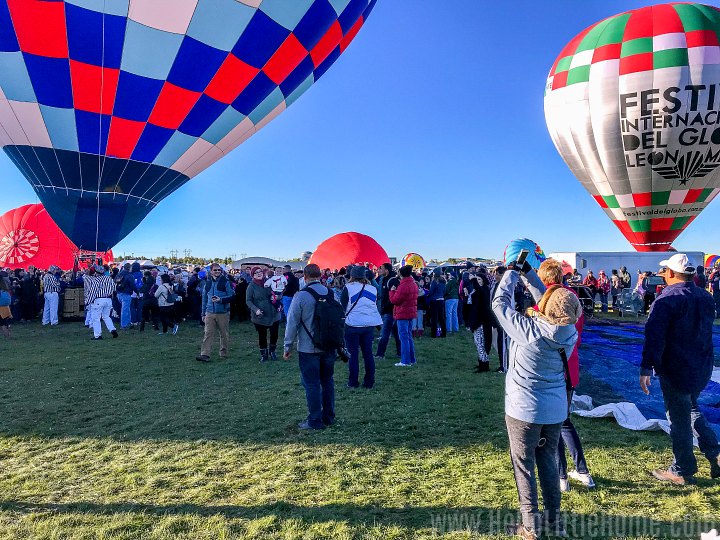 A woman photographing a hot air balloon launch with her camera phone.