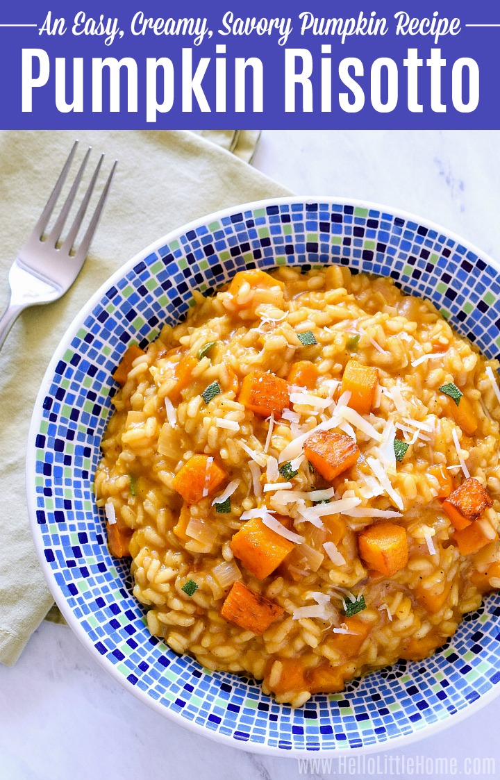 A bowl of roasted pumpkin risotto next to a napkin and fork on a marble counter.