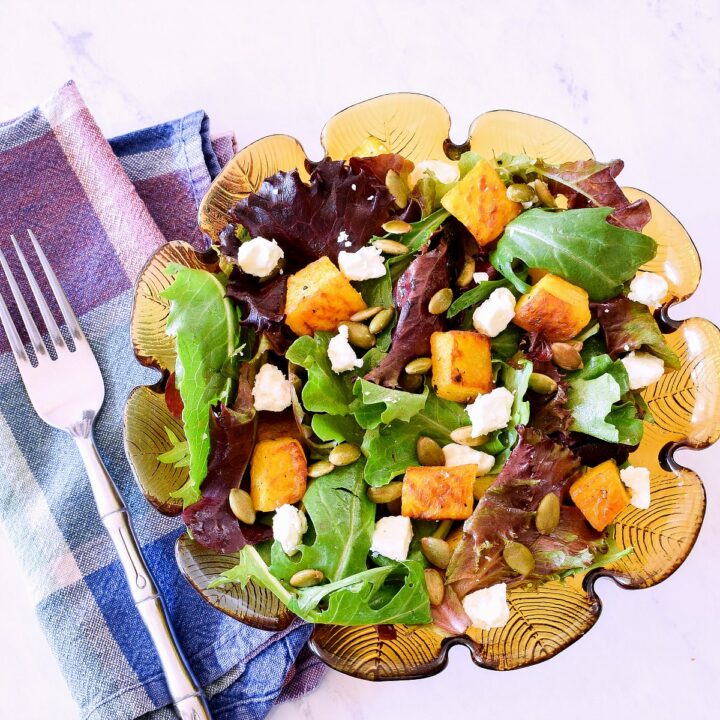 A Roasted Pumpkin Salad with Feta and Maple Dressing on a white marble counter.