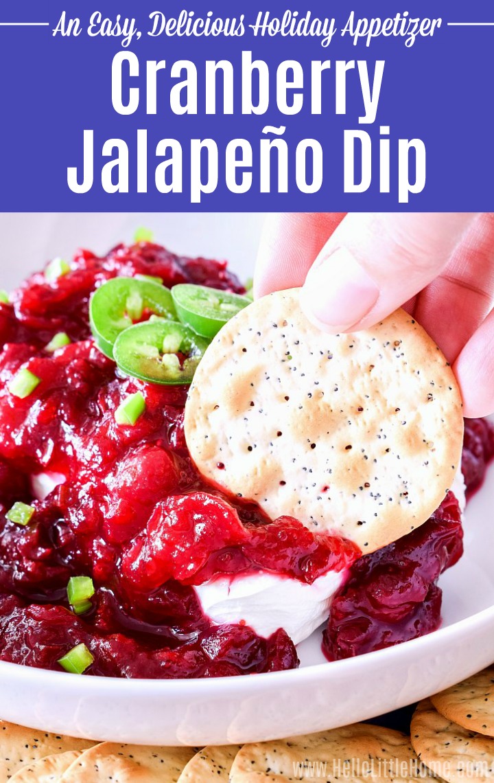 A hand dipping a cracker into Cranberry Jalapeno Dip.