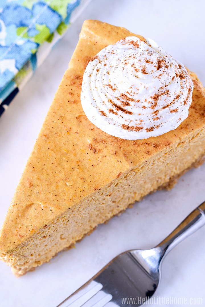 An overhead photo of a Pumpkin Cheesecake slice topped with whipped cream.