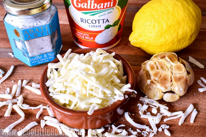 Ingredients for Baked Ricotta Cheese arranged together on a wood cutting board.