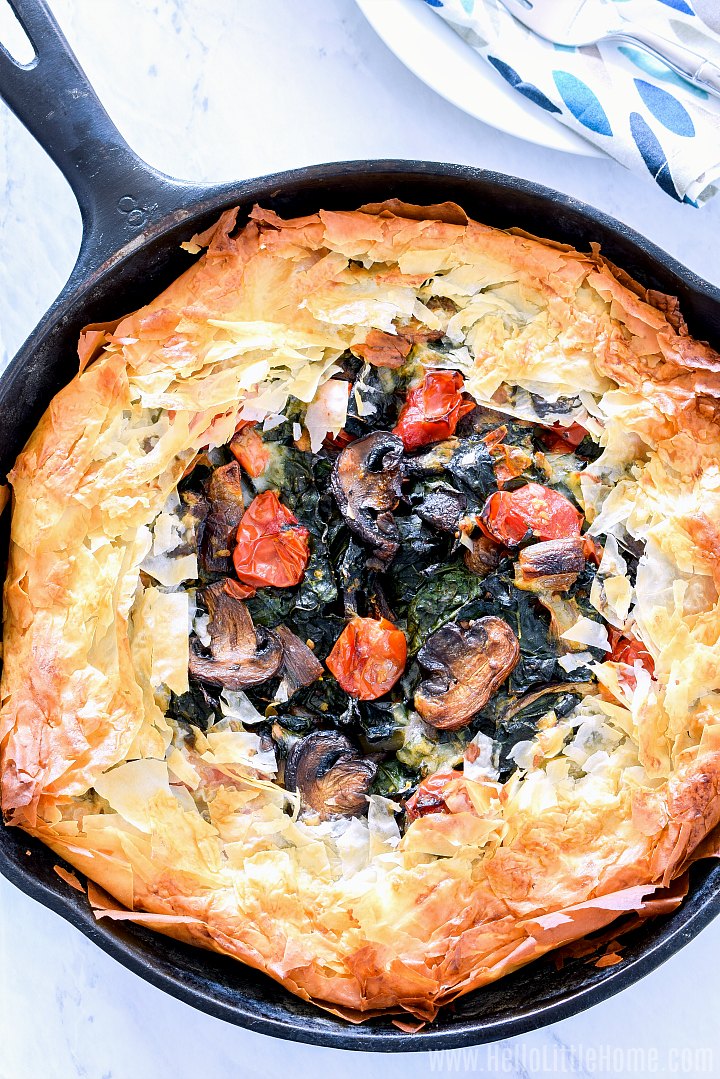 A vegetarian Vegetable Pie in a cast iron skillet on a white marble table.
