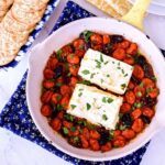 Baked Feta in a yellow skillet on a blue pot holder.