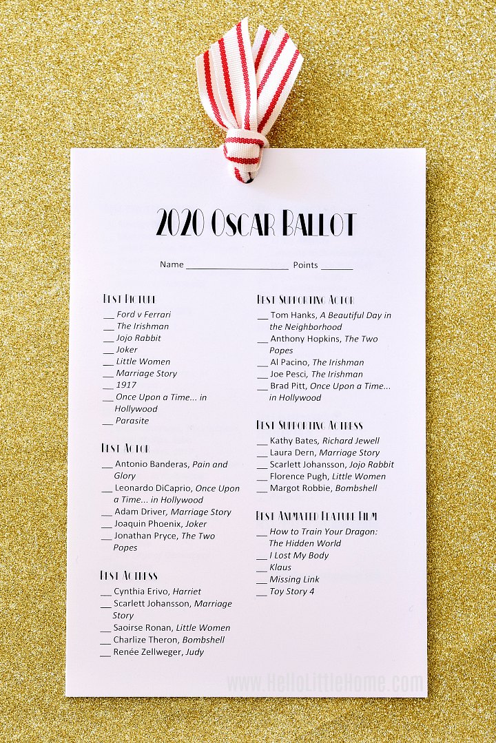 An Oscar Ballot 2020 printable tied together with ribbon and displayed on gold glitter paper.