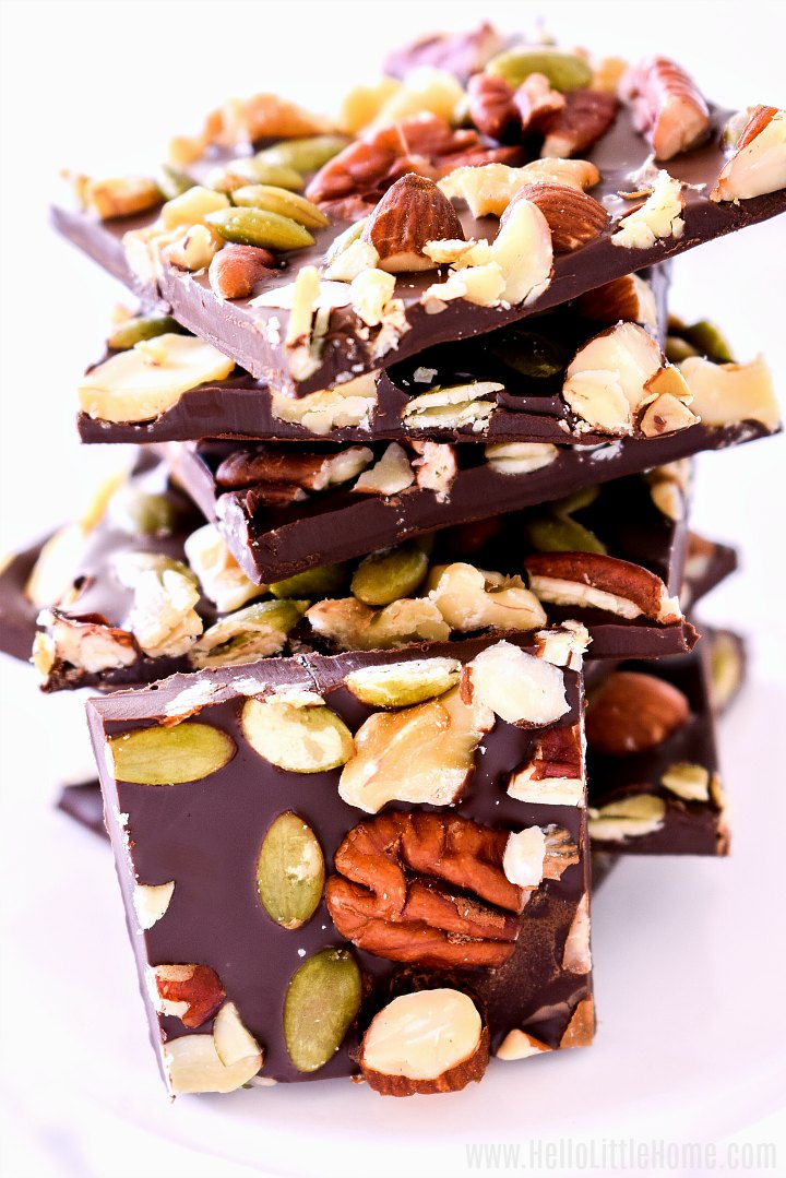 A stack of Dark Chocolate Bark with mixed nuts on a white pedestal.
