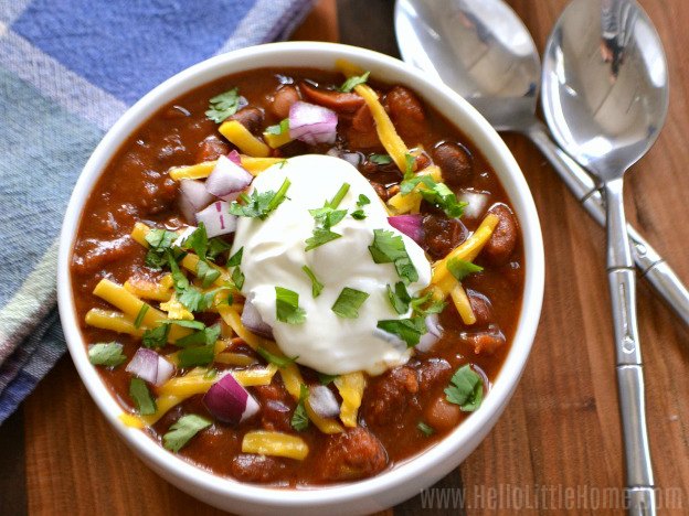 A bowl of chili topped with shredded cheese and sour cream.