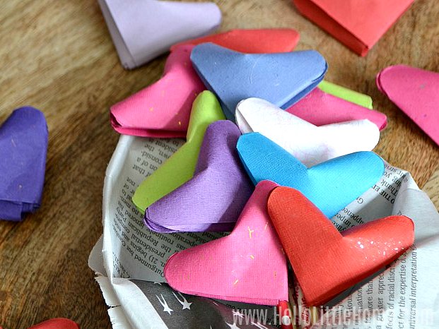 A bunch of origami hearts on a wood table.