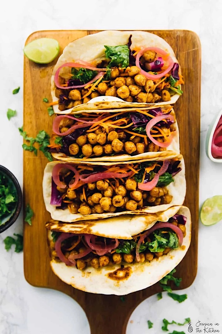 Chickpea tacos arranged on a wood cutting board.
