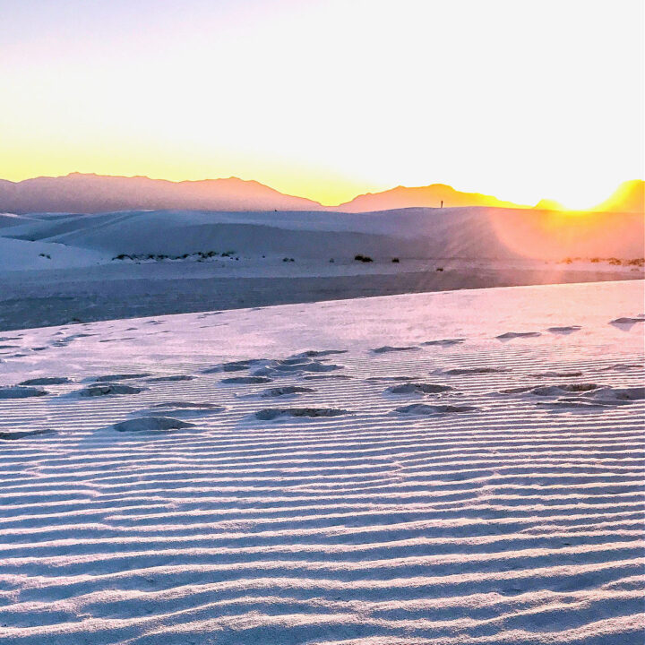 The sun setting behind the mountains surrounding White Sands National Park.