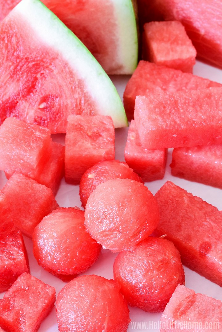 Closeup of watermelon balls and other shapes on a marble counter.