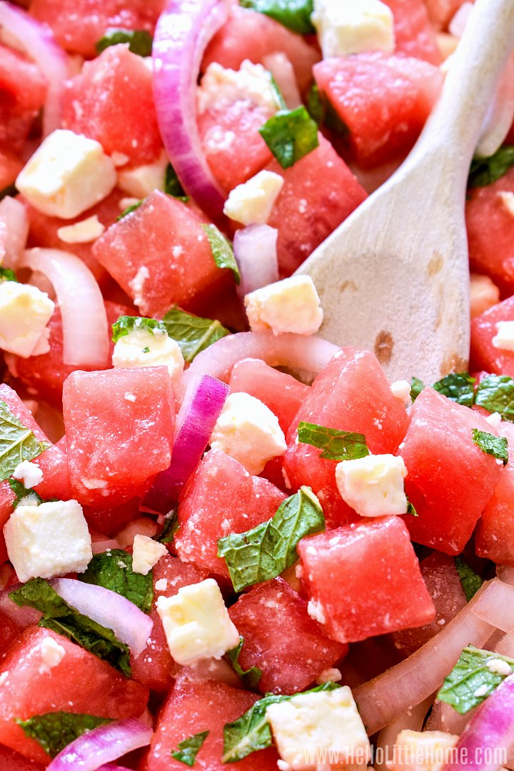 Closeup of a wood spoon stirring the finished watermelon salad.