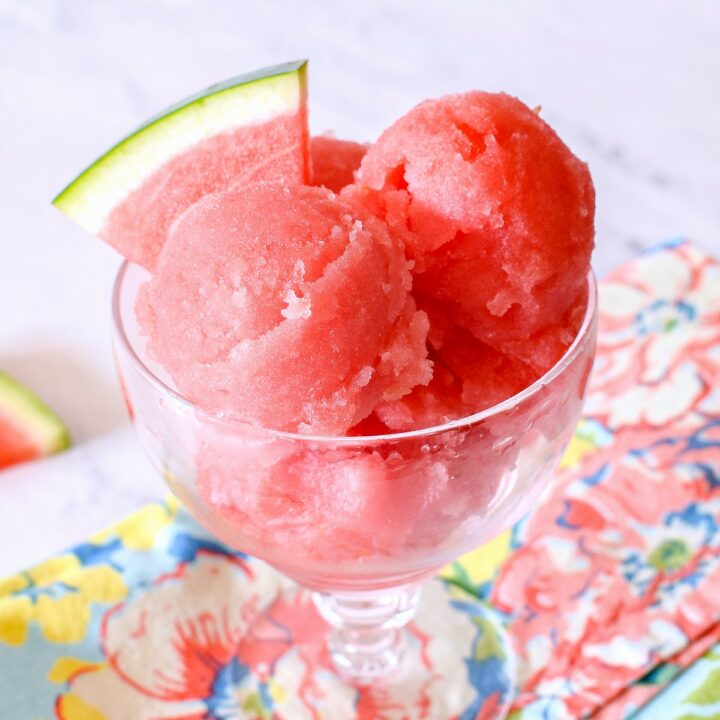 A dish of Watermelon Sorbet and a floral napkin on a marble counter.