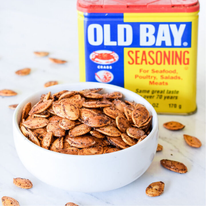A bowl of Old Bay Pumpkin Seeds with a box of seasoning behind it.
