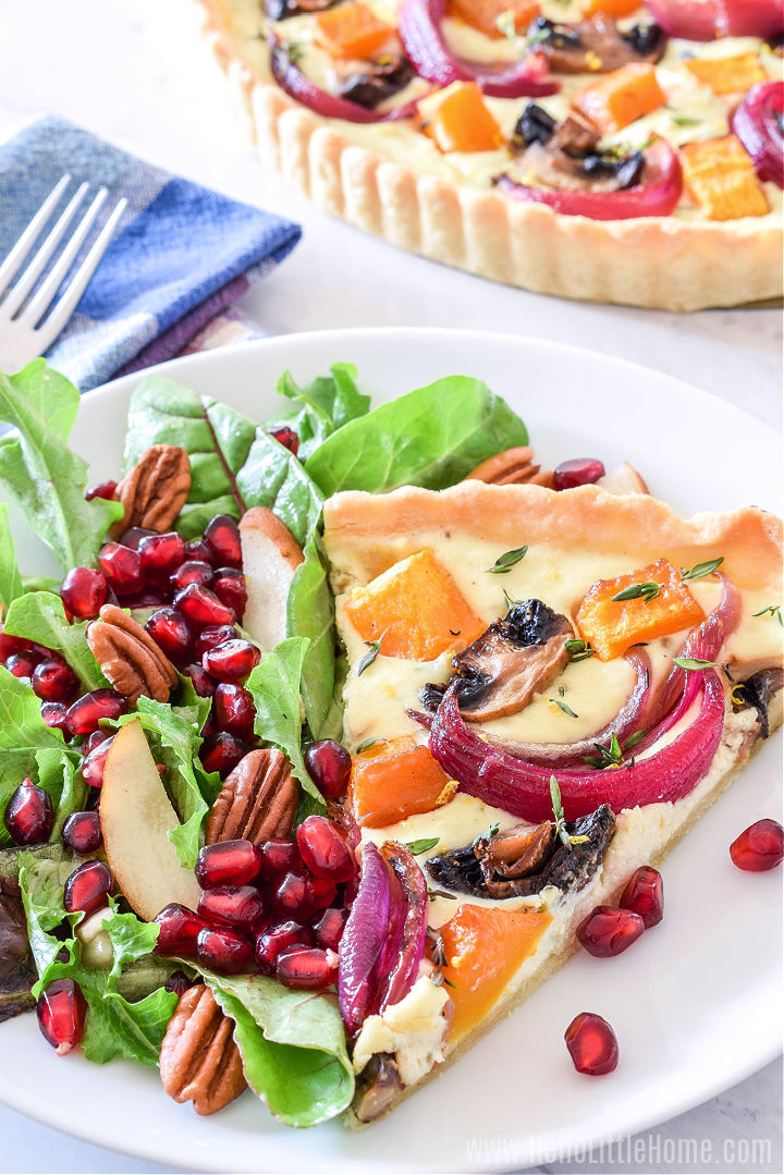 A piece of the finished recipe served with salad on a plate with the whole tart in the background.