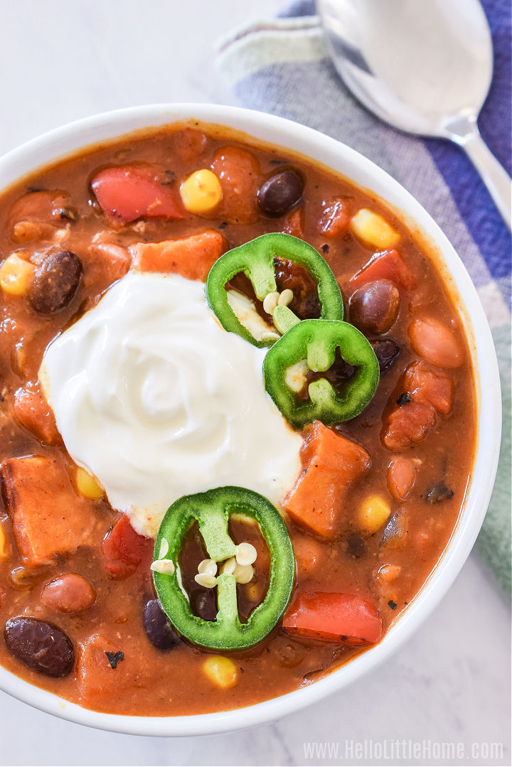A bowl of vegetarian Pumpkin Chili topped with sour cream and jalapeno slices.