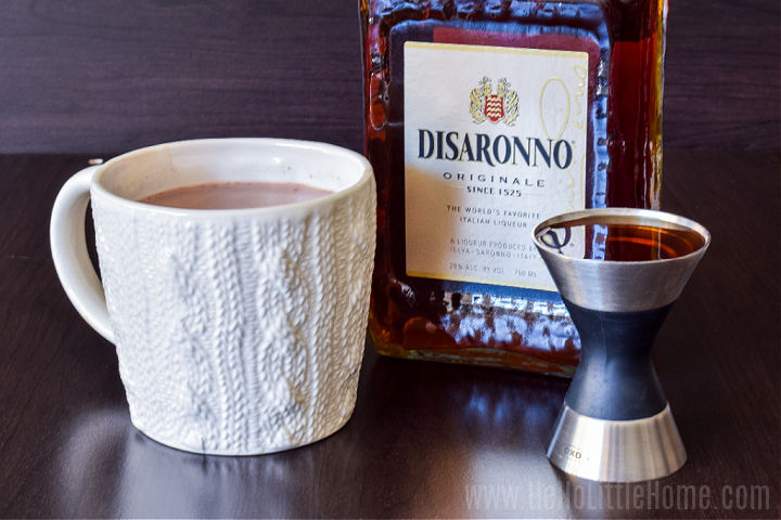 A mug of cocoa next to a bottle of amaretto.