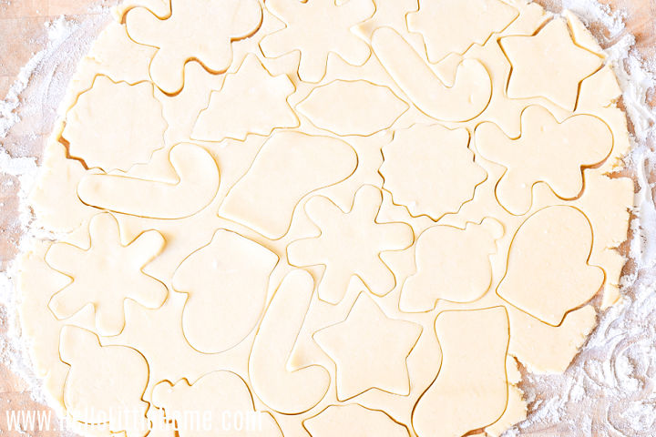 The rolled out dough on a wood board, cut with various Christmas cookie cutters.