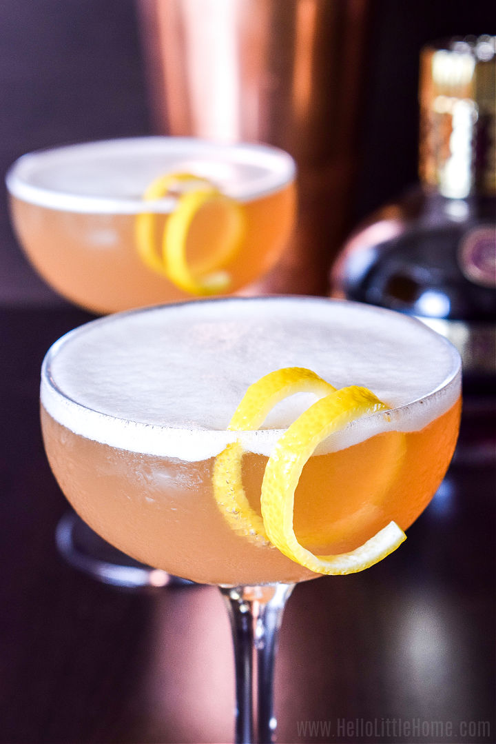 Крупный план готового коктейля с пенистым верхом и гарниром из лимонной закрутки.
