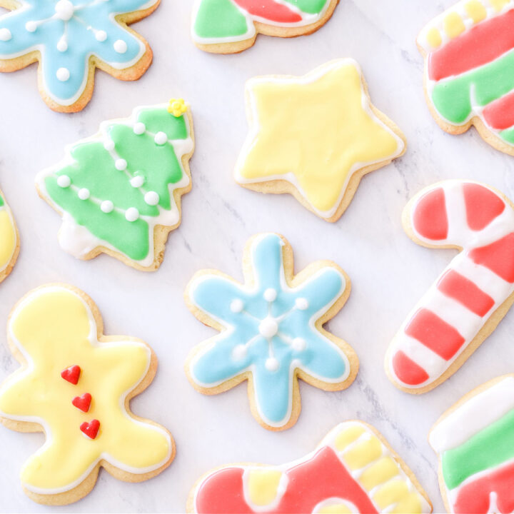 A variety of decorated Sour Cream Cut Out Cookies on a marble counter.