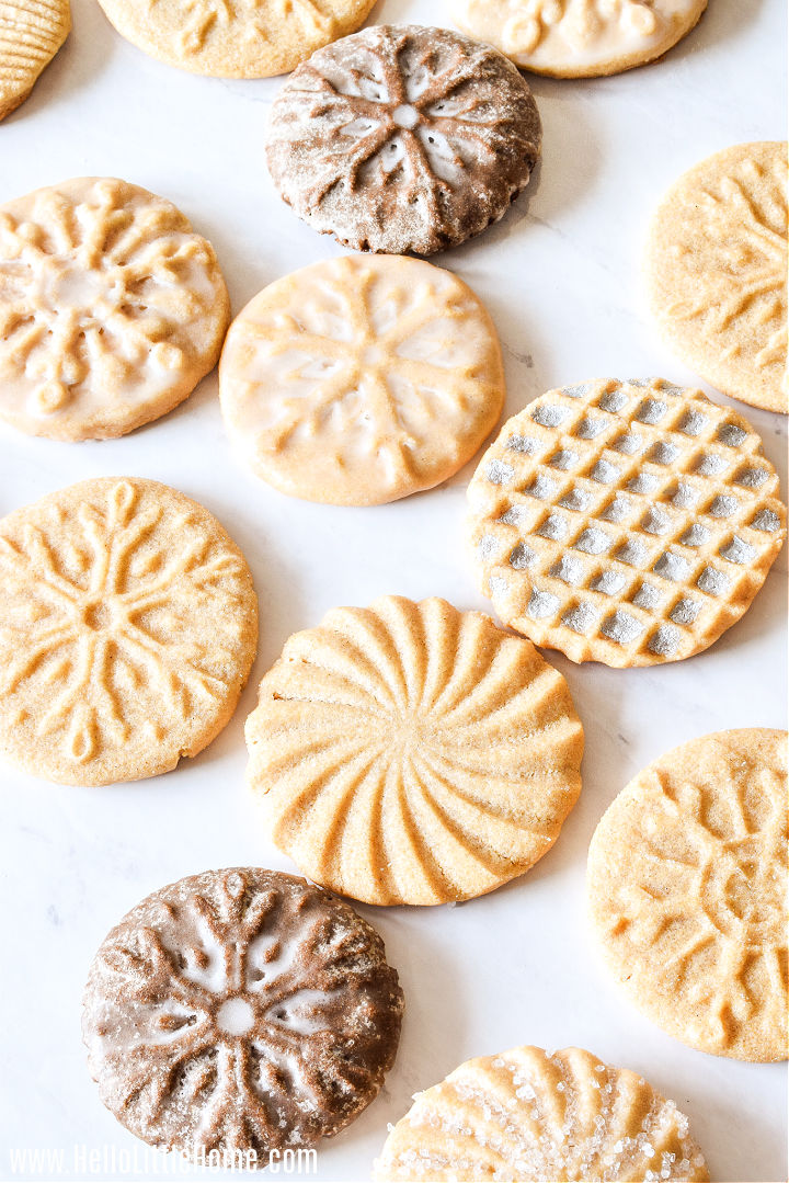 A variety of different cookie flavors and patterns scattered on a marble counter.