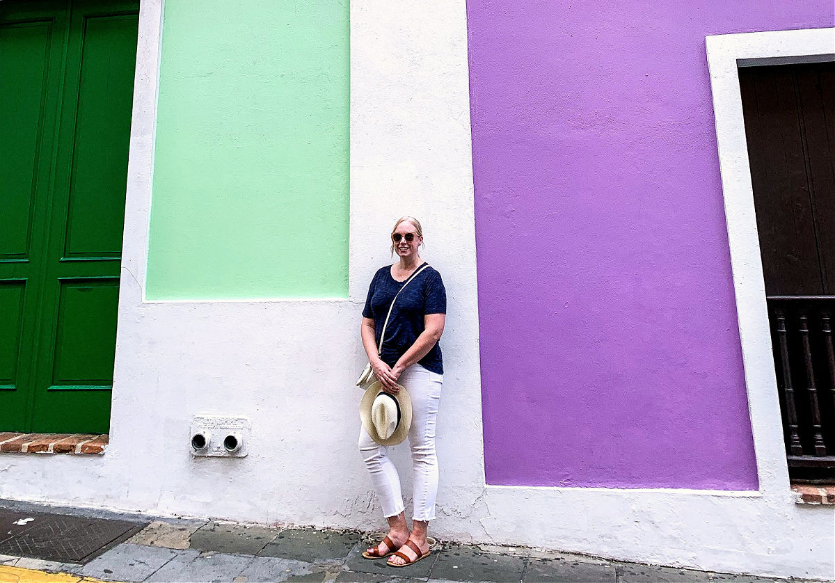 Ginnie standing between purple and green buildings in San Juan, Puerto Rico.