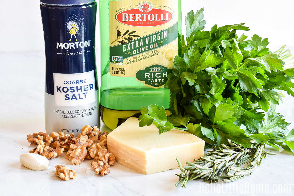 Rosemary pesto ingredients arranged on a marble counter.
