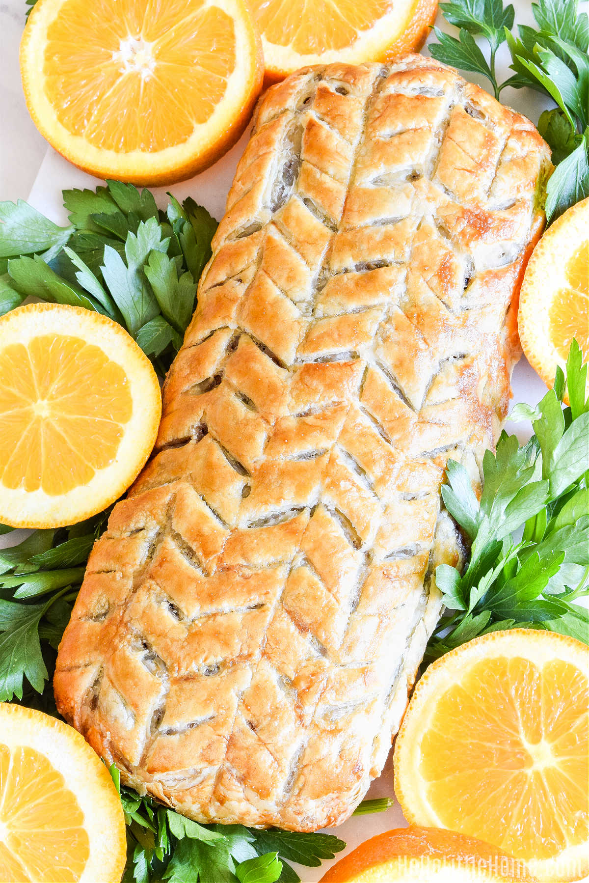 The finished Vegetarian Wellington on a platter surrounded by herbs and orange slices.