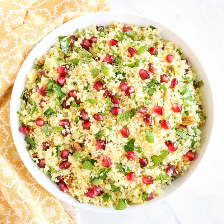 A bowl of Pomegranate Couscous Salad next to a yellow napkin.