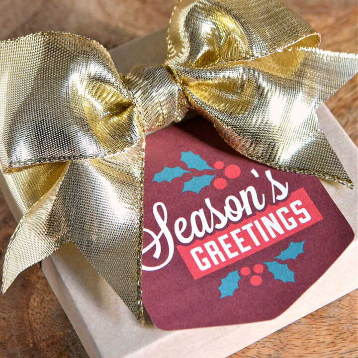 A box topped with a seasons greetings gift tag and a gold bow.