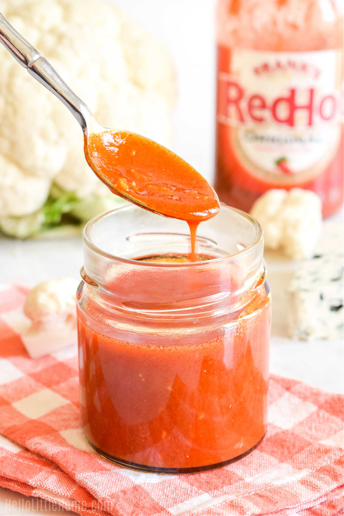A spoon drizzling the finished sauce into a jar.