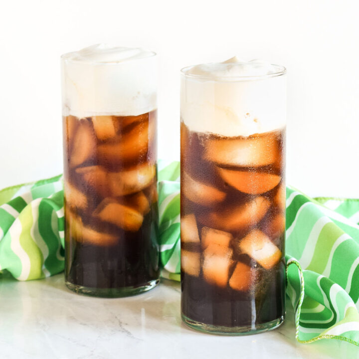 Two Irish Iced Coffees and a striped napkin on a marble counter.