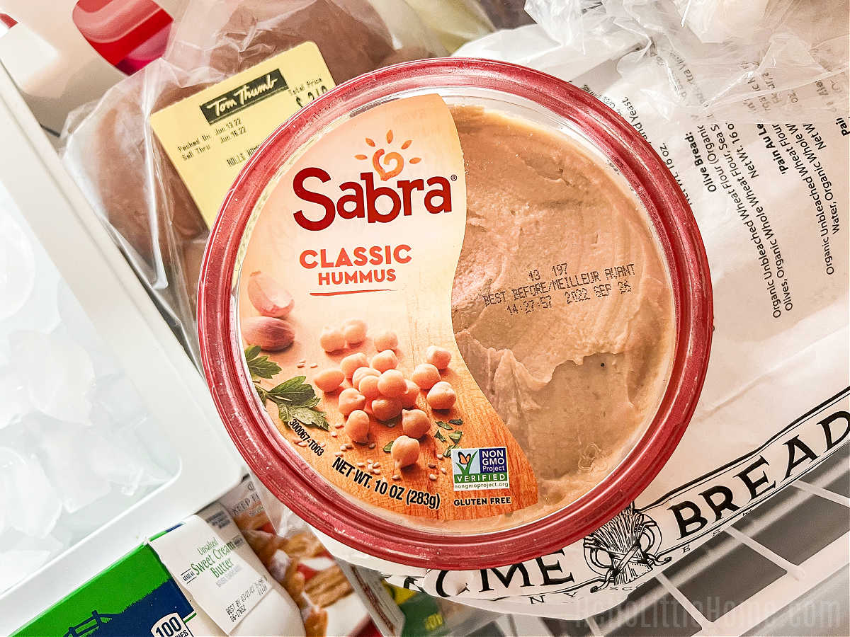 A container of store bought hummus in a freezer.