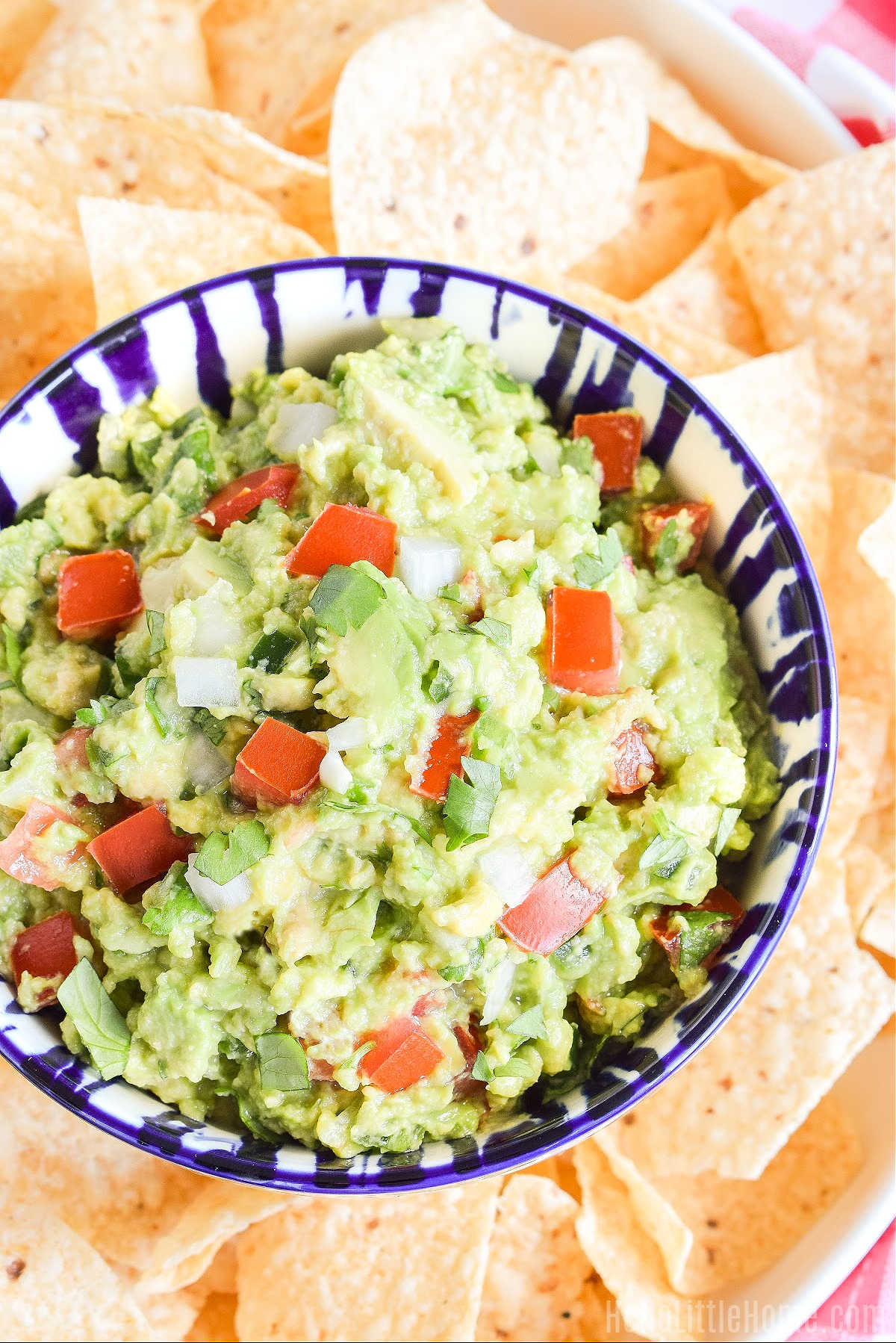 A bowl of guac and tortilla chips on a platter.