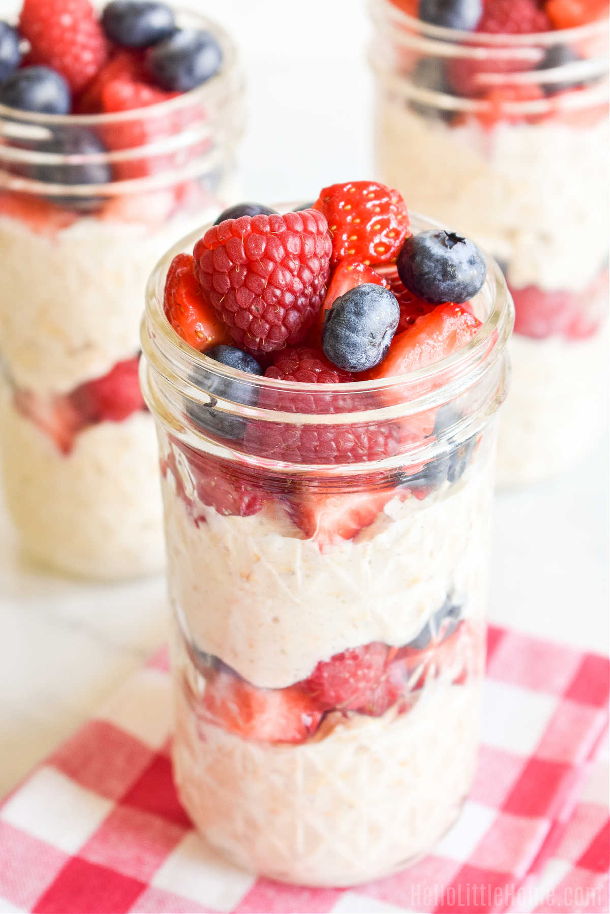 Jars of oats topped with fruit on a marble counter.